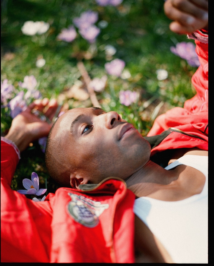 Evadney lying down on grass and flowers in red jacket 