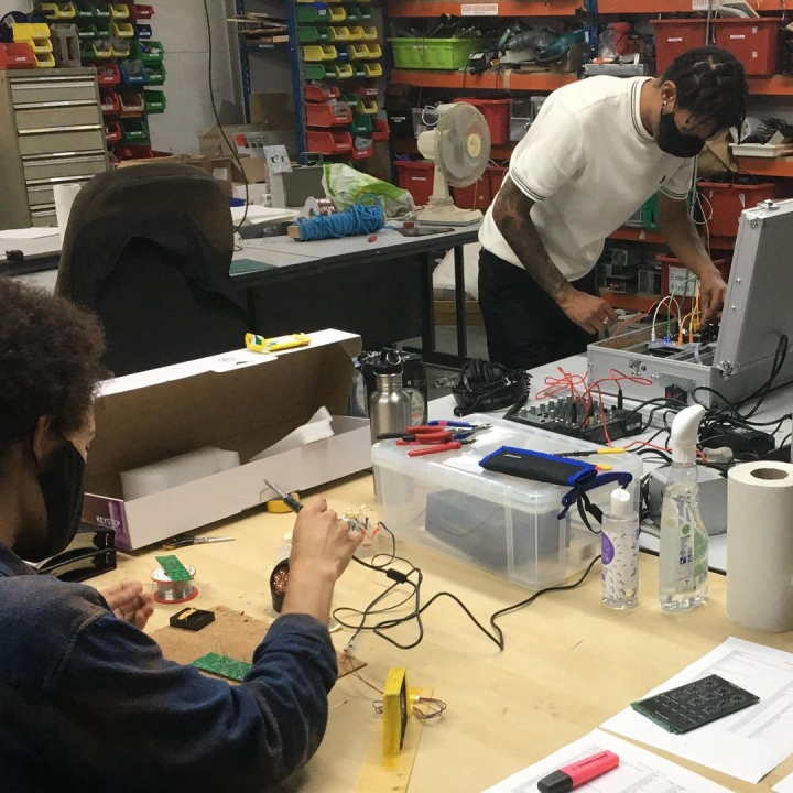 2 poeple soldering on taable 