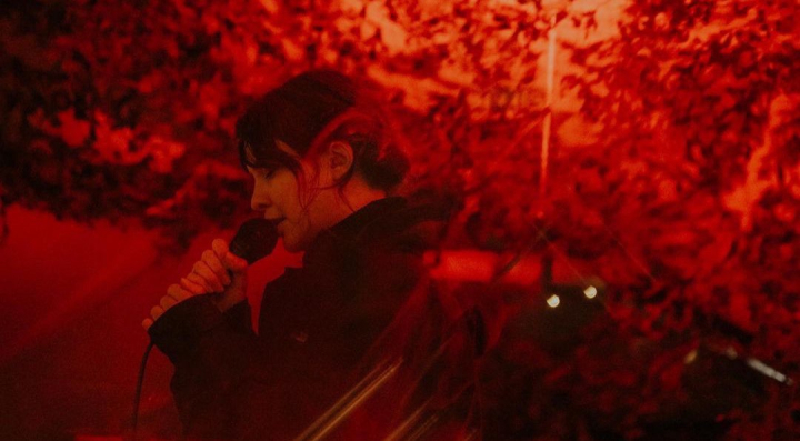 Guest singing into microphone in red lighting 