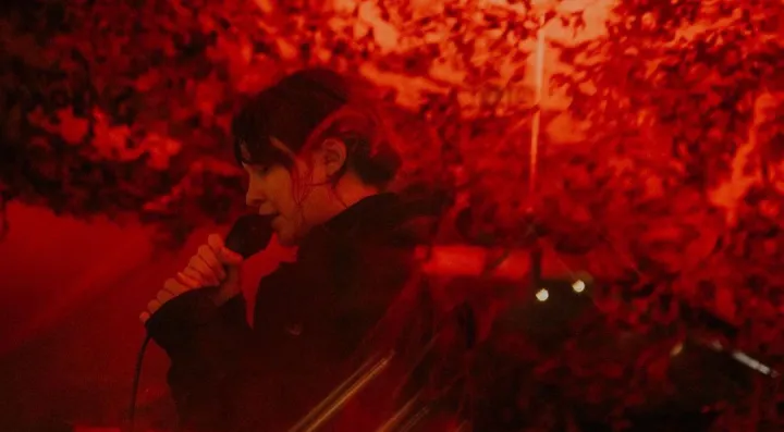 Guest singing into microphone in red lighting 